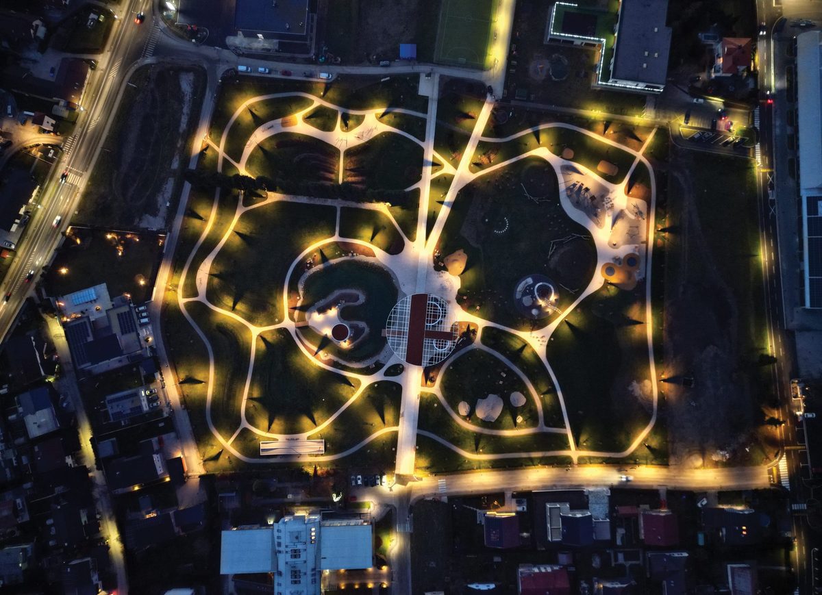 Vista aérea nocturna de un parque urbano con caminos iluminados por farolas inteligentes.